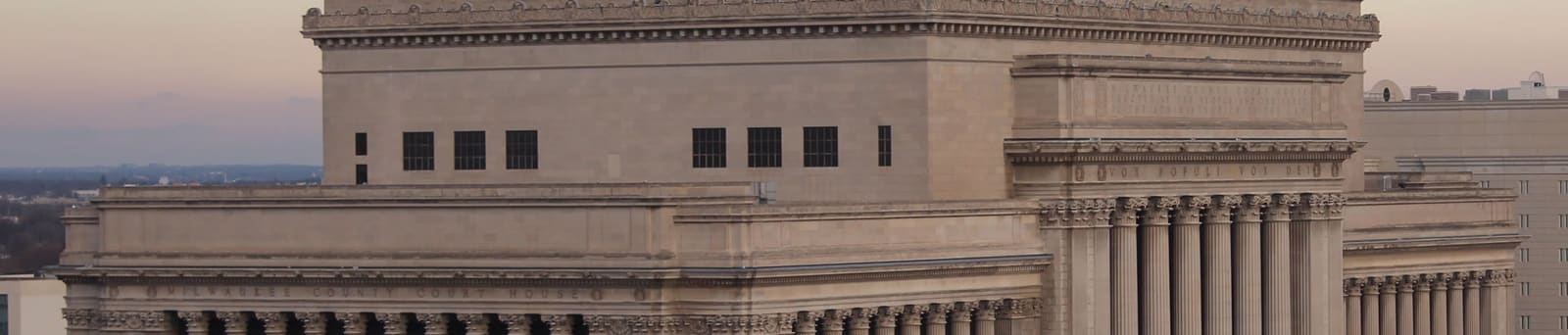 The Milwaukee County Courthouse at dusk, its neoclassical columns lit against the sky